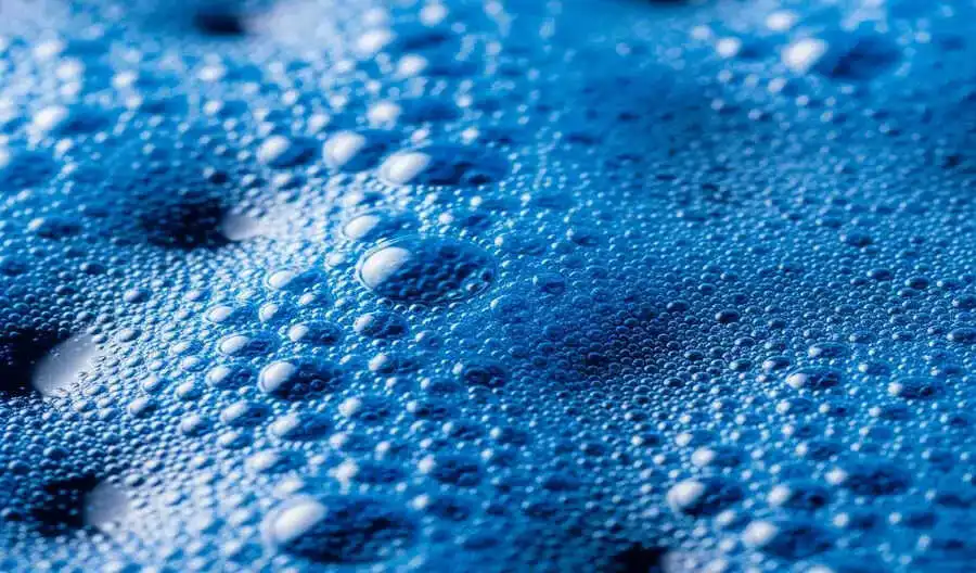 Close-up of bright blue chemical foam, showing reactive textile dye or treatment solution in industrial processing. - chemical consumption tracing in textile industry 2