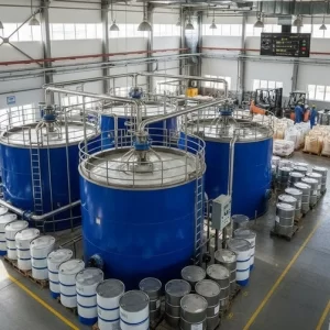Industrial setup with large blue chemical mixing tanks, drums, and raw material bags in a modern textile chemical plant. -Textile Auxiliary Chemicals Suppliers. -1