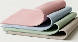 Minimal 3D render of layered rubber sheets curling at edges, soft pastel tones, smooth lighting, industrial material texture focus. -Silicone Temperature Resistance. -1