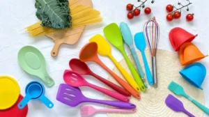 A flat-lay landscape photo showcasing a colorful set of food-grade silicone kitchen utensils neatly arranged on a clean white countertop.