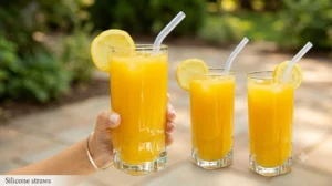 Glasses of orange juice with lemon slices and reusable silicone straws.