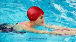 Girl wearing a red silicone swim cap and swimming in a pool.