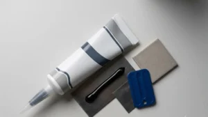 A tube, glossy bead, and smoothing tool on samples - Black Silicone Sealant -1
