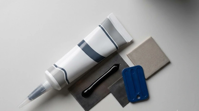 A tube, glossy bead, and smoothing tool on samples - Black Silicone Sealant -1